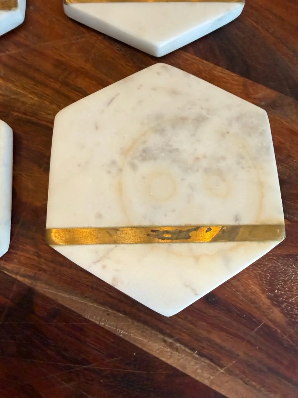 Hexagonal white marble coasters featuring a brass inlay design
